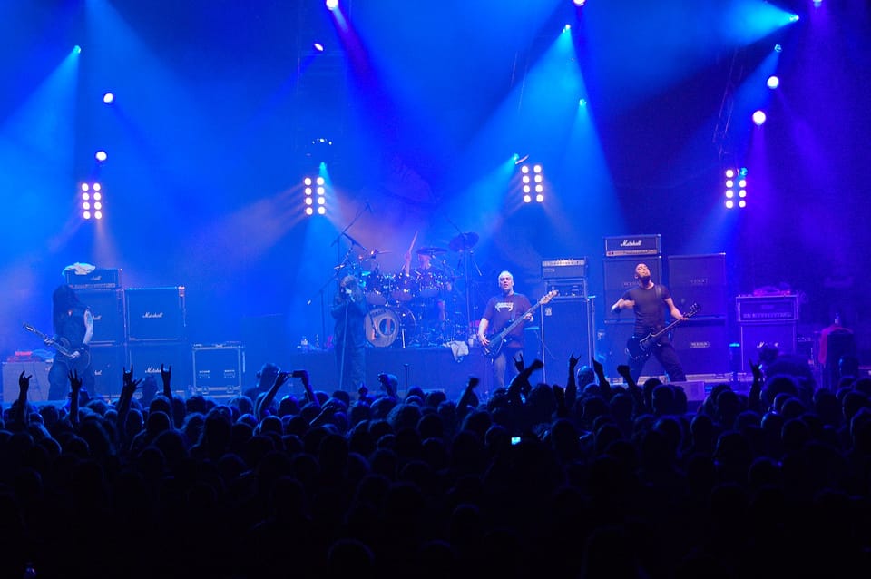 A blue hued photo of the band Paradise Lost playing on stage. 